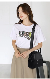Close-up of black crossbody bag with multiple zippers and wide adjustable strap