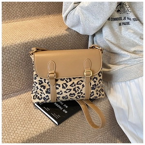 Detail of crossbody bag with brown leather flap and leopard print body on a staircase