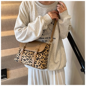 Close-up of leopard print crossbody bag with tan leather flap and golden buckle detail