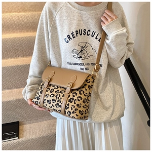 Detail of leopard print crossbody bag featuring khaki flap and dual buckle straps