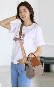 Detail of compact two-tone crossbody bag with wide adjustable strap and metal hardware