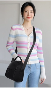 Close-up of black mini versatile crossbody bag with woven strap on striped sweater