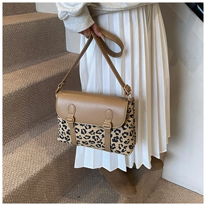 Close-up of leopard print messenger bag with brown leather flap and dual buckle straps