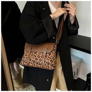 Detail view of a vintage leopard print crossbody bag with brown leather straps and metal buckles