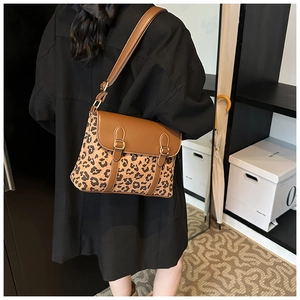 Detail of leopard print crossbody bag with brown leather flap and golden buckles