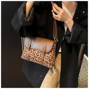 Detail of leopard print crossbody bag with brown leather flap and adjustable strap