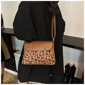 Detail of leopard print crossbody bag with brown leather flap and golden hardware on model