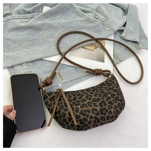 Detail of leopard print crescent crossbody bag with brown leather knotted strap accents