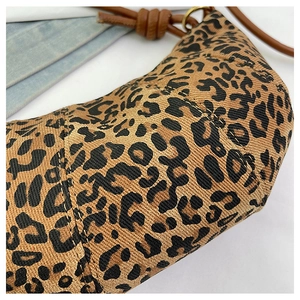 Close-up of leopard print fabric texture and brown leather strap with knot detail