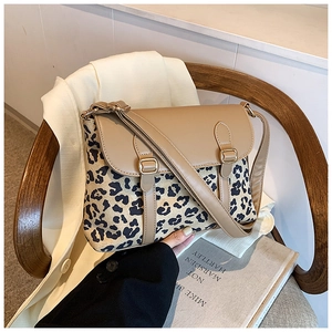 Detailed close-up of leopard print canvas and khaki leather crossbody bag on a wooden chair