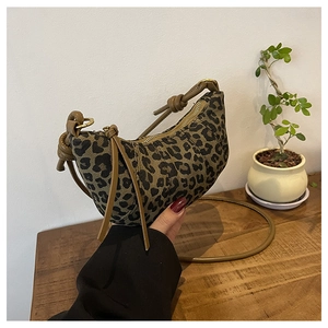 Detail view of leopard print crescent bag with leather knotted handle and metal zipper