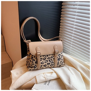 Detail of a leopard print flap crossbody bag resting on a white blazer in a warm setting
