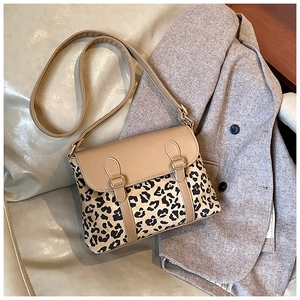 Close-up of leopard print crossbody bag with khaki leather trim and gold metal buckles