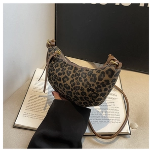 Close-up of leopard print crescent bag with leather trim and gold hardware details