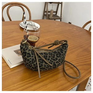 Macro detail of the leopard print crescent bag with brown leather strap and gold hardware