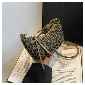 Close-up of leopard print crescent bag with brown knotted strap on a book