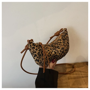 Detail of trendy leopard print crescent bag with golden zipper and brown leather strap