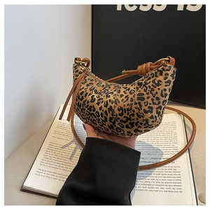Close-up of leopard print crescent bag with adjustable knotted shoulder strap and zipper