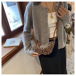 Close-up of leopard print crescent crossbody bag with brown leather strap on model