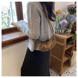 Detail of leopard print crescent crossbody bag with brown leather strap and curved zipper
