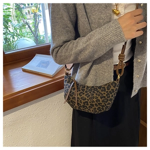 Detail of leopard print crescent bag with brown leather trim and knotted strap