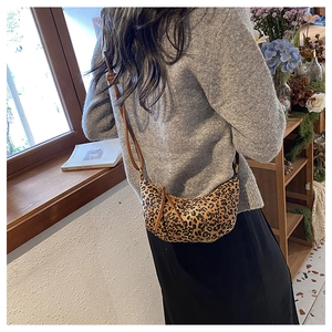 Detailed view of leopard print crescent bag featuring knotted straps and zipper closure