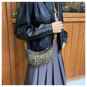 Detailed shot of leopard print crescent bag featuring unique shoulder strap knot design