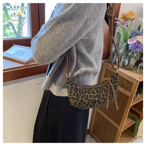 Detail shot of leopard print crescent bag with leather strap and gold hardware