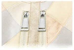 Close-up of dual silver rectangular zippers on textured patchwork faux leather backpack