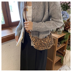 Detailed view of vintage leopard print crescent bag with leather strap on a model