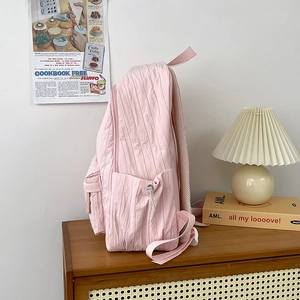 Lightweight pink pleated backpack in Korean style for school students on a wooden cabinet