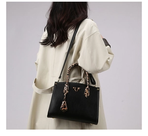 Close-up of leopard print handles and metal logo detail on a black leather tote bag