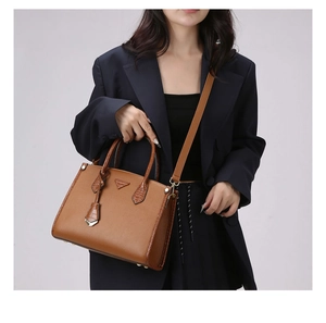 Detail of a brown leather handbag featuring a cross-grain texture and twin top handles