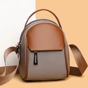 Modern grey mini backpack and crossbody bag with brown leather accents and woven strap