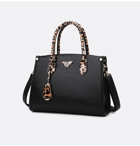Detail of black pebbled leather handbag with leopard print triangle and gold hardware