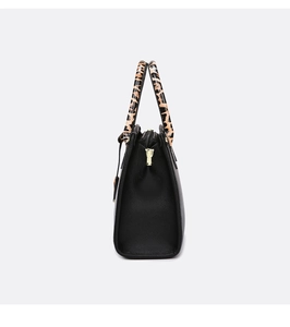 Detailed side view of black pebble leather tote featuring leopard print handles and gold hardware