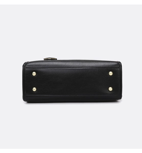 Detail of black lychee grain leather handbag base with four golden protective metal feet