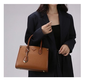 Detail of caramel leather handbag with crocodile pattern splicing and triangle plaque
