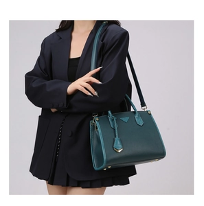 Detail of dark green leather tote with crocodile embossed trim and gold hardware accents
