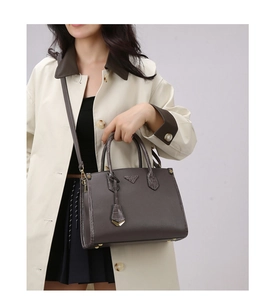 Detail view of dark grey tote with crocodile pattern trim and triangular metal logo