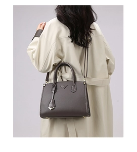 Detail of dark brown tote bag with triangle logo and embossed leather on a model