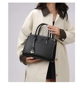 Detail of black pebbled leather tote with croc-embossed handles and triangle logo plate