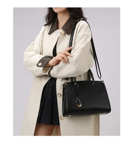 Detail of black pebbled leather tote bag with crocodile texture straps shown on model