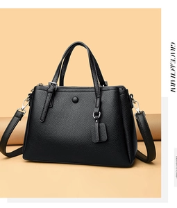 Detail of black lychee leather handbag featuring gold metal zipper and sturdy dual handles