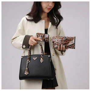 Detail view of large black tote bag with leopard print wallets and triangle logo plaque