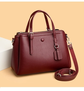 Detail of burgundy lychee pattern leather handbag with silver hardware and detachable strap