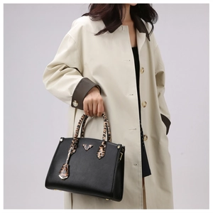 Detail of black pebbled leather tote featuring leopard print handles and metal feet