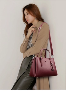 Close-up of dark burgundy lychee pattern leather tote bag shown on a trench coat model
