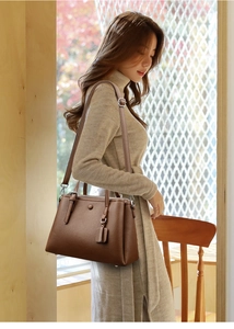 Detail of dark brown lychee leather handbag with metal buckle and shoulder strap