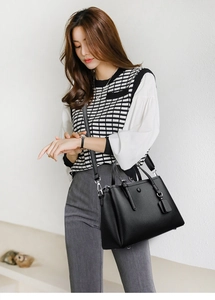 Detail of black litchi texture tote bag featuring silver hardware and adjustable strap